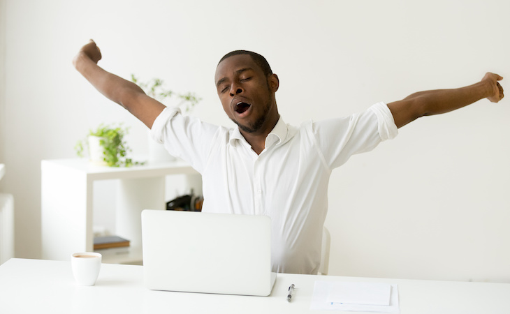 tired person yawning and stretching at workplace