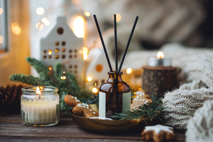 Aromatic home apartment diffuser with the fresh pine fragrance, gingerbread cookies scent. Fir tree branches, essential oils, candle, holiday decor. Cozy festive atmosphere, Christmas spirit