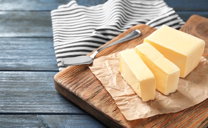 Cut block of butter on wooden board