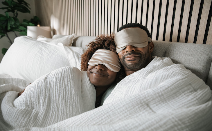 Man and woman snuggled up wearing eye masks