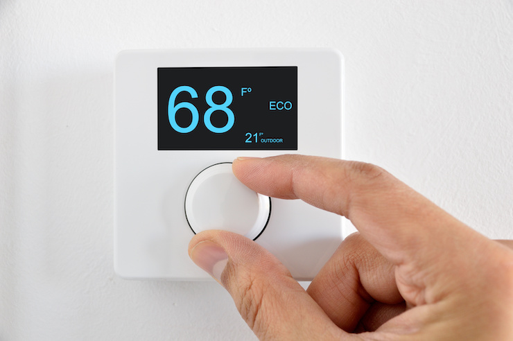 Person turning down thermostat to 68 degrees