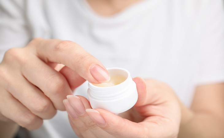 Woman taking cosmetic petrolatum from jar